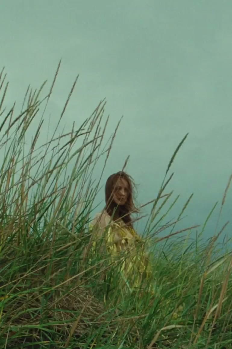 Woman in a yellow dress standing in tall grass