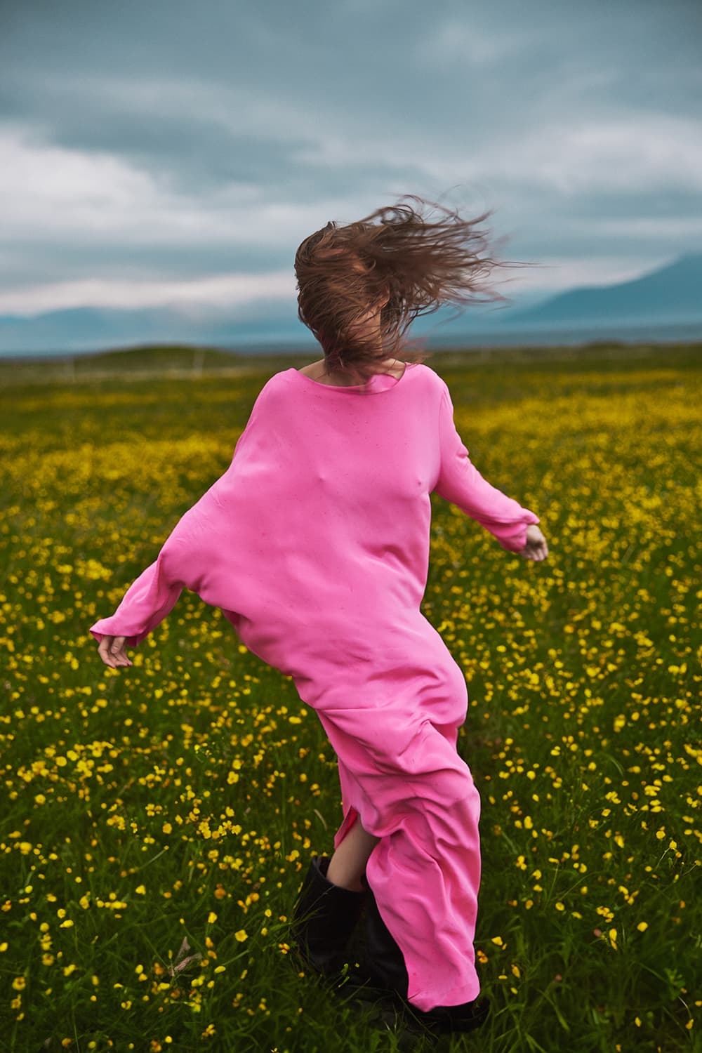 Woman in a pink dress in a field of yellow flowers